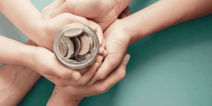 Child and parent hands holding money jar.