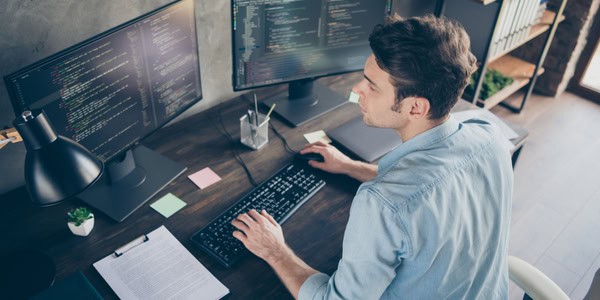 Man sitting at computer with code on screen