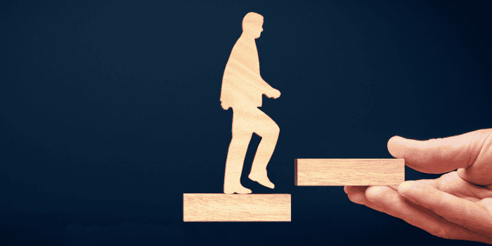 Wooden man walking up wooden stairs.